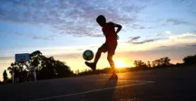Niño jugando a la pelota mientras atardece 