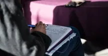 Persona participante del taller anotando en una libreta 