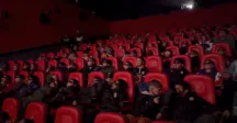 Niñas y niños están en el cine mirando una pelicula 